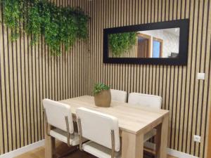 una mesa con sillas blancas, un espejo y una planta en Apartamento Peace Home Astillero en El Astillero