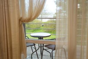 a balcony with a table and chairs in front of a window at Beach Guesthouse Lenkas in Saraiķi