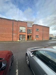 a red car parked in front of a brick building at Iacomm Newbridge 2 bed apt in Newbridge