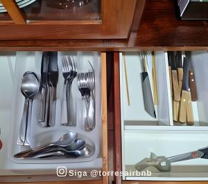 a drawer filled with utensils in a cabinet at Apartamento com vista para o mar in Torres