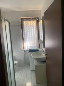 uma casa de banho com um lavatório, um WC e uma janela. em Appartamento con piscina e giardino privati em Peschiera del Garda