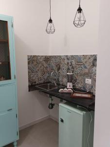 uma cozinha com um balcão e um lavatório e duas luzes em A casa di Mimì em Bari
