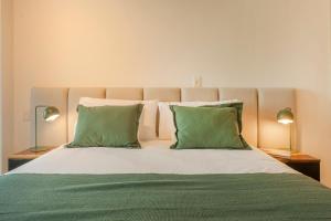 1 cama grande con 2 almohadas verdes y 2 lámparas en Viví y Disfrutá el Lujo en Torre Decó Recoleta Armani powered by Argenhost -902-, en Buenos Aires