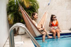 Dos mujeres sentadas en una hamaca junto a una piscina en El Machico Hostel, en Panamá