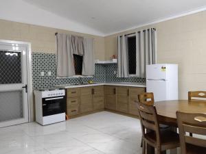 cocina con mesa y nevera blanca en Fale Mailani-2 rooms/AC/hotwater, en Vaitele
