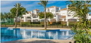 a villa with a swimming pool in front of a building at La Torre Golf Resort in Roldán