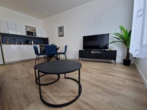 un soggiorno con tavolo, sedie e TV di Cosy & Work - 2 chambres- Centre a Brest