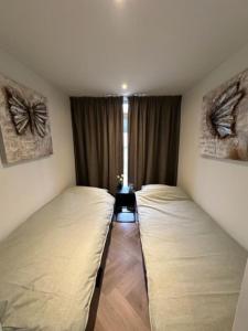 two twin beds in a room with a window at Luxe boshuisje Arlo in Ermelo! in Ermelo