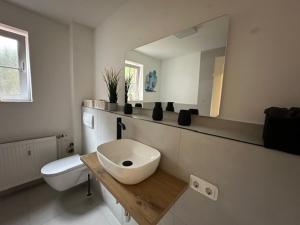 Baño blanco con lavabo y espejo en Whg 1 Charmante Ferienwohnung in Scharbeutz -Ihr perfektes Zuhause am Meer, en Scharbeutz