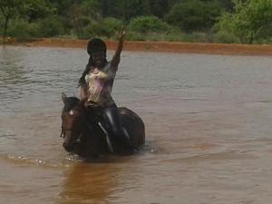 a person riding a horse in the water at Thandile River Cottages in Moheme