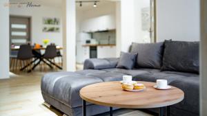 a living room with a couch and a wooden table at Wonder Home - Apartament Enya blisko deptaka, miejskiego placu zabaw i Parku Zdrojowego in Świeradów-Zdrój