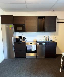 una cocina con electrodomésticos de acero inoxidable y armarios marrones en Rentalux Apartments at Vivansborg en Timrå