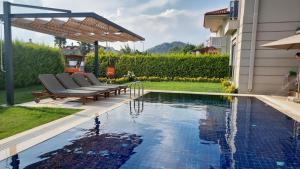 a swimming pool with lounge chairs next to a house at Dalyan Villa Carmen-1 in Dalyan