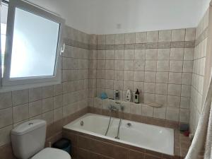 a bathroom with a tub and a toilet and a window at ΔΩΜΑΤΙΟ ΧΑΛΑΡΩΣΗΣ ΜΕ θέα και ησυχία in Patra