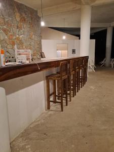 a long wooden bar in a room with a stone wall at Villas Roberto's Bistro Mirador in Troncones