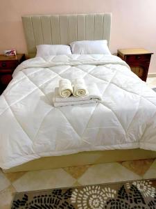 Una cama blanca con dos toallas encima. en Studio Merit Pyramids View, en El Cairo
