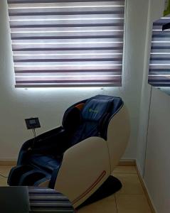 a chair sitting in a room with a window at Astrolax Cinema with Jacuzzi & 4D Massage Chair in Ponce
