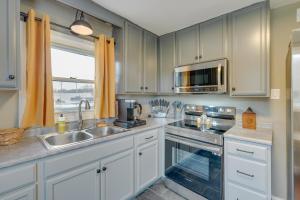 een keuken met witte kasten, een wastafel en een magnetron bij Quaint Kingsport Apartment Near Greenbelt Trail! in Kingsport