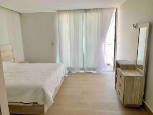 a bedroom with a bed and a dresser and a mirror at Ocean View Condo in Mazatlán +25 photos