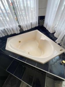 een badkamer met een wit bad en gordijnen bij Suíte de Luxo no centro, com hidromassagem e closet in Sinop