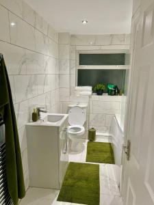 a white bathroom with a toilet and a sink at Swanmore in Derby