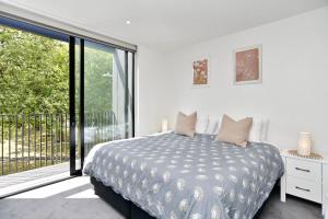 a white bedroom with a bed and a large window at Worcester Terrace 201 in Christchurch