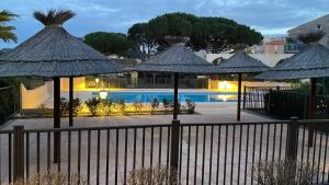 eine Gruppe von Sonnenschirmen vor einem Pool in der Unterkunft Studio Mezzanine Piscine presqu'île de Giens in Hyères