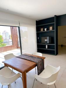 une salle à manger avec une table en bois et des chaises blanches dans l'établissement Pausa Soñada Junin BsAs -Dpto de 2 dormitorios con terraza y parrilla, à Junín