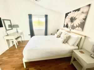 a white bedroom with a large bed and a desk at The Applewood Lodge in Heytesbury