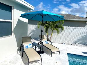 two chairs and a blue umbrella next to a pool at Heated Pool Family Retreat- Games, Everglades, Keys in Miami