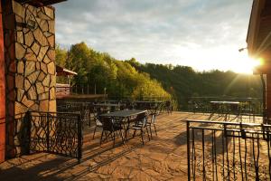 a patio with tables and chairs with the sun setting at Păstrăvăria Crasna Bogiri in Izvoarele