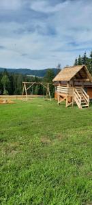 un parco giochi con padiglione in legno in un campo di Domek przy Złotym Groniu a Istebna