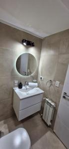 een badkamer met een witte wastafel en een spiegel bij Departamentos del oeste in Bariloche