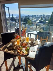 een tafel met eten en sinaasappelsap op het balkon bij Departamentos del oeste in Bariloche