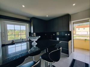 a kitchen with a black counter and some chairs at Casa Fronteiriça in Valença