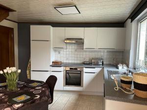 a kitchen with white cabinets and a table with a tableablish at Maison au cœur d'Houffalize in Houffalize