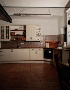 a kitchen with white cabinets and a tile wall at Ferienhof Bahlens-Schur in Friedland