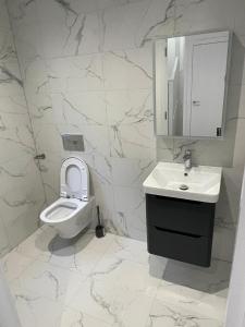 een witte badkamer met een toilet en een wastafel bij Hemel Hives in Hemel Hempstead