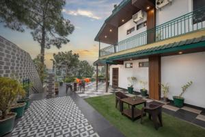 eine Terrasse mit Tischen und Stühlen auf einem Gebäude in der Unterkunft Kasauli Height in Kasauli