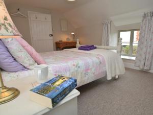 a bedroom with a bed with a book on a table at 3 Bed in Bridport 57688 in Mosterton