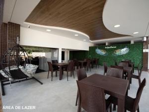 a restaurant with tables and chairs and a green wall at ApartDamani - short rental apartments in Foz do Iguaçu
