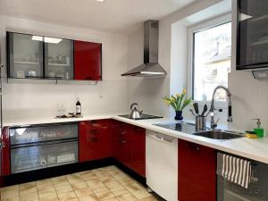 a kitchen with red cabinets and a sink and a window at Sunshine House in Olivone