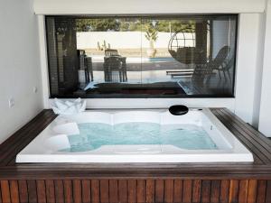a jacuzzi tub in a room with a large window at ApartDamani - short rental apartments in Foz do Iguaçu