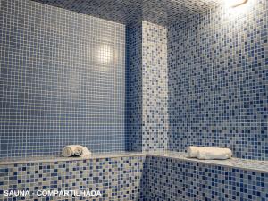 a blue tiled bathroom with two sinks and towels at ApartDamani - short rental apartments in Foz do Iguaçu