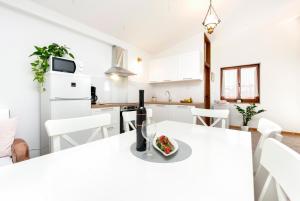 a white kitchen with a table with a bowl of food on it at Charming House Nino with a fenced yard in Krmed