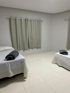 2 bedden in een witte kamer met gordijnen bij Apto apoio Serra da Capivara in São Raimundo Nonato