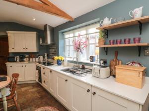a kitchen with white cabinets and a sink and a window at Chapel Cottage in Ebberston