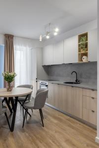 a kitchen with white cabinets and a table and chairs at Joy Garden Apartment - Free Private Parking - Wellness Jacuzzi SPA Extra Fee in Sinaia +33 photos