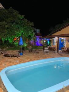 uma piscina à noite com uma mesa e um guarda-sol em Pousada Jardim de Minas em Serra do Cipó