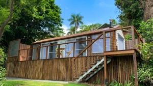ein Haus mit einer Terrasse und einer Treppe in der Unterkunft Rainforest Gardens - Luxury Hillside Accomodation with Views to Bay & Islands in Mount Cotton
